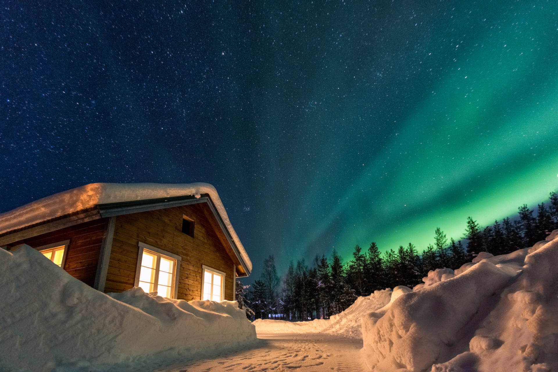 Vue sur les aurores boréales et le chalet - Voyage de luxe Laponie